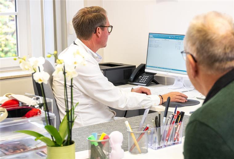 Ein Patient sitzt im Behandlungszimmer beim Arzt.