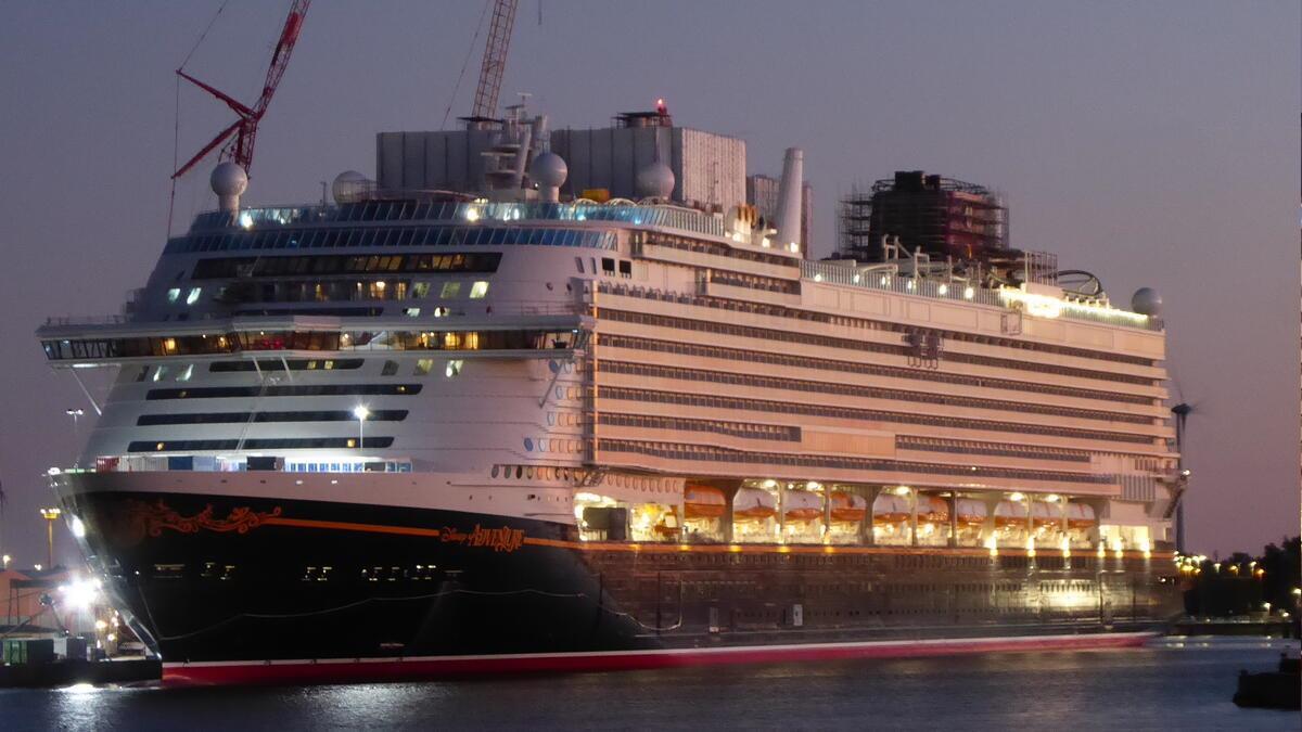 Verzögerung bei der „Disney Adventure“: Kreuzfahrtschiff bleibt in Bremerhaven Die „Disney Adventure“ liegt beleuchtet am Abend im Bremerhavener Überseehafen an der Lloyd Werft. Auf dem Deck sind Baugerüste und Kräne zu erkennen.