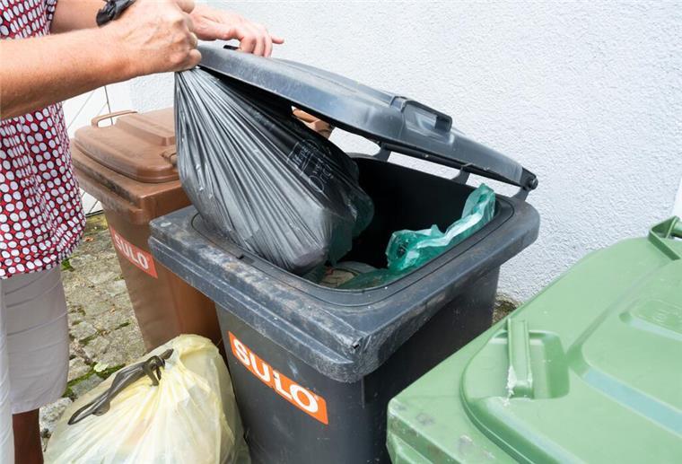 Ein Mann in kariertem Hemd wirft einen Müllsack in den Restmüll. Seit Mai gelten strengere Regeln: Wer seine Biotonne falsch befüllt, kann auf dem Müll sitzen bleiben. Und muss womöglich Bußgelder zahlen.