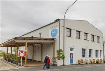 Eine alte Industriehalle, jetzt ein Café: Davor laufen Spaziergänger.
