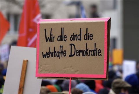 Selbstgemaltes Plakat mit der Aufschrift „Wir alle sind die wehrhafte Demokratie“.