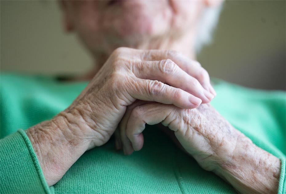 Eine 100 Jahre alte Bewohnerin eines Seniorenhauses faltet ihre Hände