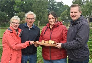 Vier Personen halten ein Brett mit Süßkartoffeln in den Händen.