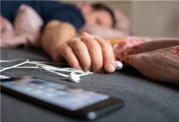 Ein Mann schläft mit einem Smartphone neben sich.