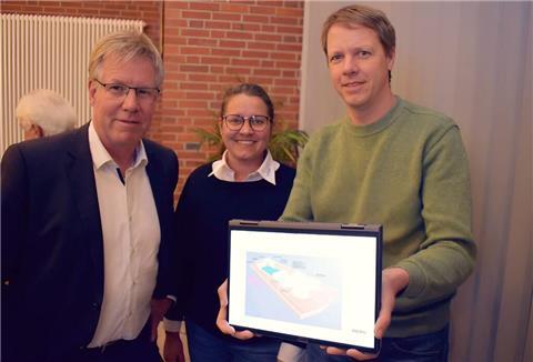 Zwei Männer und eine Frau zeigen etwas auf einem Laptop