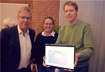 Zwei Männer und eine Frau zeigen etwas auf einem Laptop