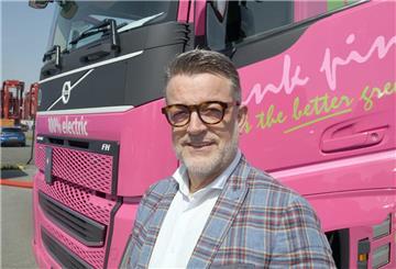 Mann vor einem pinkfarbenen Lastwagen