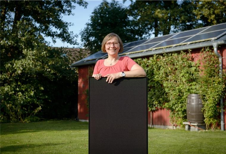 Eine Eigenheimbesitzerin präsentiert ein Photovoltaikmodul.