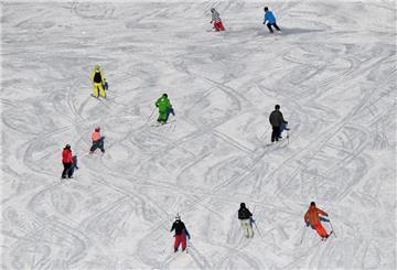 Skifahrer fahren bei Sonnenschein auf einer Skipiste.
