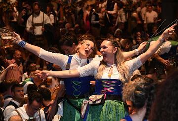 Frauen im Dirndl stoßen mit Maßkrügen an