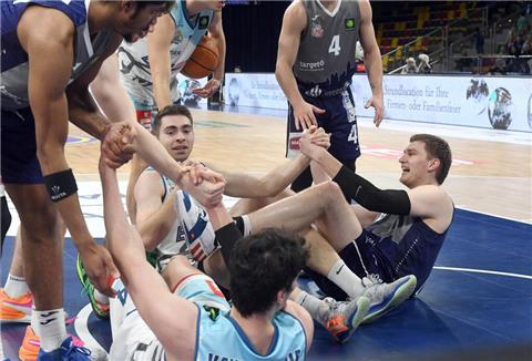 Basketballspieler kämpfen um einen Ball und liegen zum Teil am Boden.