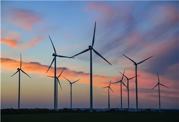 Farbenprächtig leuchten Wolken am Morgenhimmel kurz vor Sonnenaufgang über einem Windpark