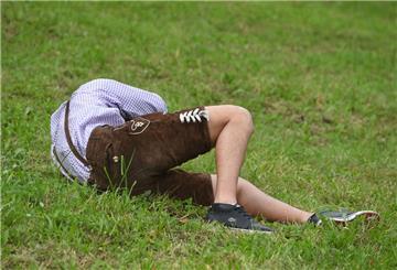  Ein Besucher liegt stark betrunken auf einer Wiese am Rande des Oktoberfestes. 