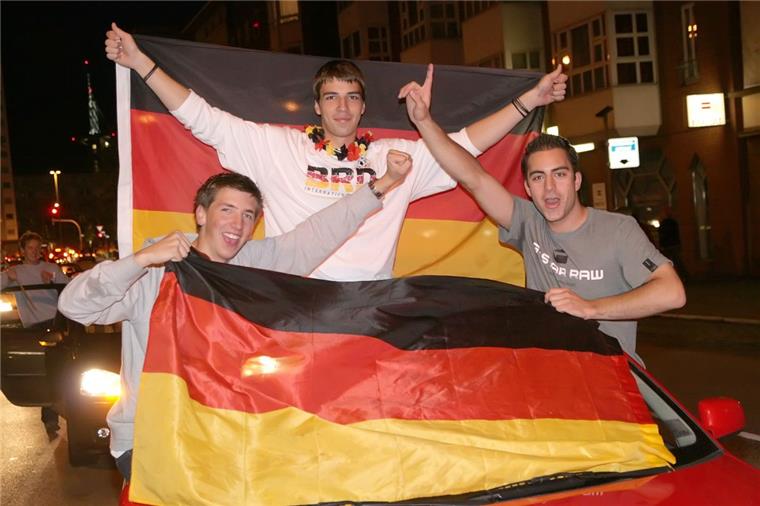 Deutsche und portugiesische Fans feiern gemeinsam auf der Straße in Bremerhaven. Fahren sollte das Auto aber nicht, wenn alles mit Flaggen bedeckt ist.