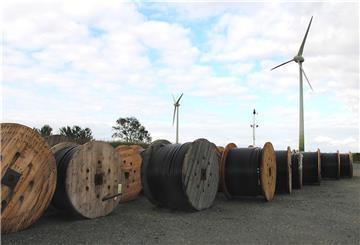 Kabel für den Stromtransport liegen vor zwei Windrädern