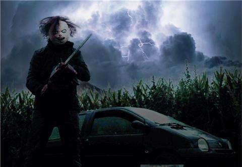 Horrorfigur mit Säge vor dunklem Himmel und Auto.