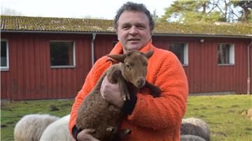 Sönke Hofmann hält auf dem Gelände der Dreptefarm ein Lamm im Arm
