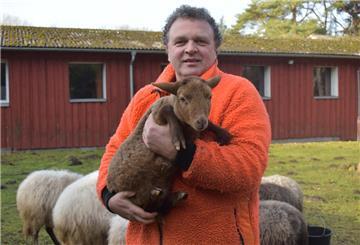 Sönke Hofmann hält auf dem Gelände der Dreptefarm ein Lamm im Arm