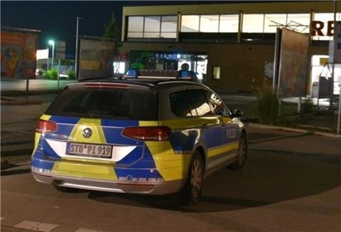 Polizeiauto in der Nacht auf Parkplatz vor Supermarkt.