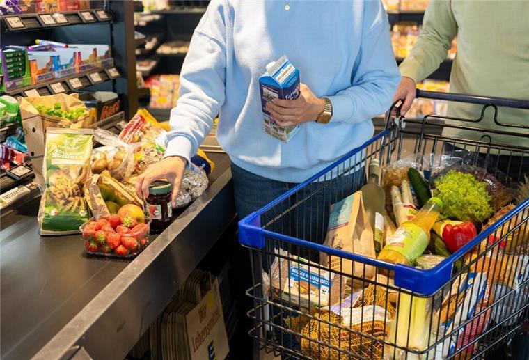 Ein Kunde stellt Produkte an einer Supermarktkasse aufs Laufband.