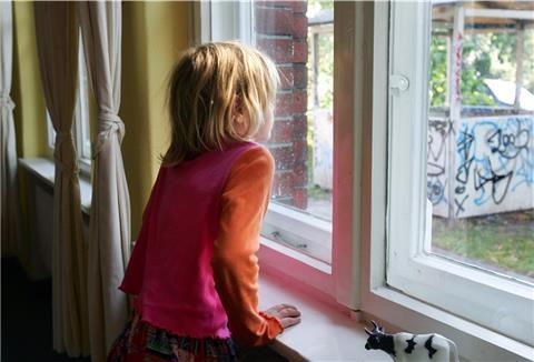 Ein kleines Mädchen schaut aus einem Fenster