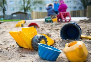 Spielzeug liegt in einem Sandkasten in einer Kindertagesstätte.