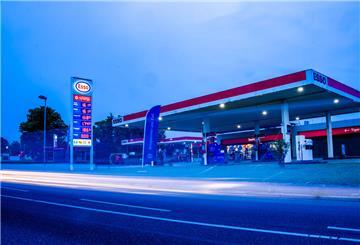  Auto fahren am Morgen an einer Tankstelle vorbei an deren Preistafel die aktuellen Literpreise für Kraftstoff angezeigt werden. 