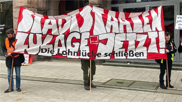 „Stadtstaaten - Zulage jetzt! - Die Lohnlücke schließen“ steht auf einem Plakat, das Demonstrierende vor dem Gewerkschaftshaus halten.
