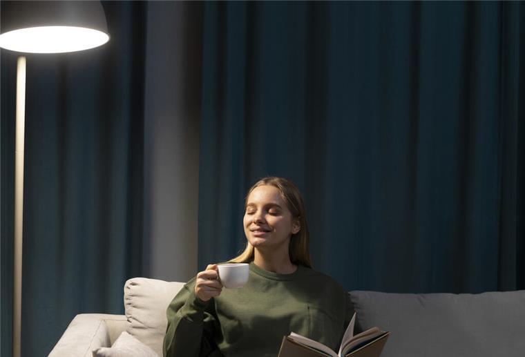 Die besten Tipps für mehr Licht in der Wohnung Frau sitzt auf Sofa und liest.