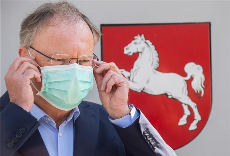Stephan Weil (SPD), Ministerpräsident Niedersachsen, steht vor der Staatskanzlei und zieht einen Mundschutz an.