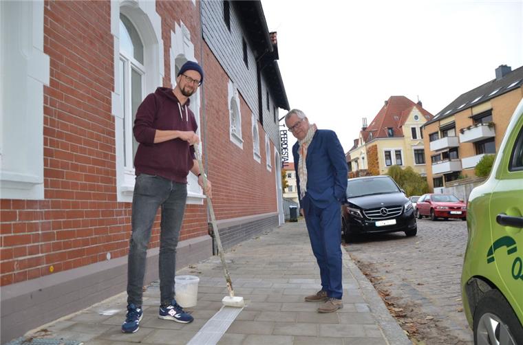 Stipendiat Sebastian Dannenberg (links) beginnt mit dem Streifen auf dem Bürgersteig vor der Künstlerwohnung in der Gartenstraße. Klaus Becké bewundert dabei seine ruhige Hand.  