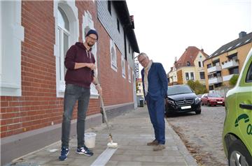 Stipendiat Sebastian Dannenberg (links) beginnt mit dem Streifen auf dem Bürgersteig vor der Künstlerwohnung in der Gartenstraße. Klaus Becké bewundert dabei seine ruhige Hand.  