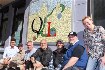 Stolz auf das in wochenlanger Kleinarbeit erstellte Mosaik, das auf die Quartiersmeisterei Lehe in der Uhlandstraße 28 hinweist (von rechts): Quartiersmeisterin Brigitte Hawelka, die Förderwerk-Mitarbeiter Henry Wiese, Axel Mahler, Jörg Fricke, Stefan Schlie und Sascha Johann sowie Hauseigentümer Tim Thiemann.  