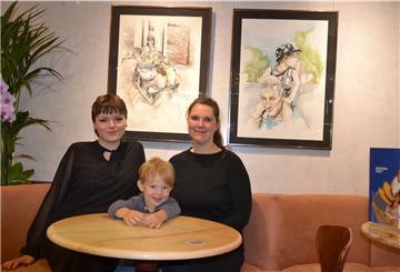Zwei Frauen sitzen zusammen mit einem kleinen Kind an einem runden Tisch in einem Eiscafé.