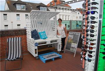 Strandkorb und Liege für Wartende, Sonnenbrillen und mehr für Touristen: Geschäftsleiterin Ina Niestaedt vor dem Info-Pavillon an der Kaje, der sein Angebot ergänzt hat.