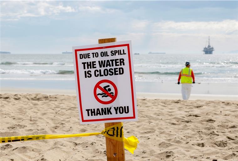 Ein Schild mit der Aufschrift "due to oil spill the water ist closed" ist am Strand aufgestellt. 