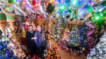 Susanne und Thomas Jeromin stehen inmitten von Weihnachtsbäumen im Wohnzimmer ihres Hauses.