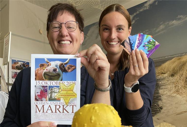 Herbstmarkt und offener Sonntag: In Nordenham dreht sich wieder alles um Ochsen Svenja Faehse von NMT präsentiert den Flyer zum Ochsenmarkt, ihre Kollegin Sandra Jankowsky die neuen Nordenham-Gutscheinkarten.