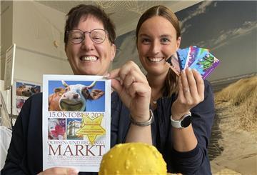 Svenja Faehse von NMT präsentiert den Flyer zum Ochsenmarkt, ihre Kollegin Sandra Jankowsky die neuen Nordenham-Gutscheinkarten.