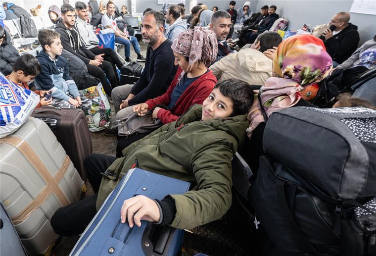 Symbolfoto: Flüchtlinge aus unterschiedlichen Ländern warten in einer Erstaufnahmeeinrichtung auf einen Bus.