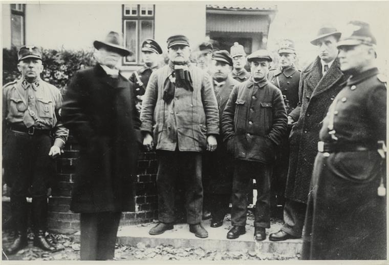 Das Schicksal des einzigen Tarmstedter Juden Täter und Opfer: Vor dem Haus von Erich Neugarten in der Zevener Gartenstraße haben der Führer des Zevener SA-Sturms Wilhelm Schnase (links) und seine Männer unter den Augen eines Polizisten (rechts) und seiner Kollegen Erich Neugarten (Zweiter von rechts), Hermann Samson (Vierter von rechts), Bernhard Blumert (Sechster von rechts), vermutlich Kurt Deichmann (hinter Blumert), Albert Rosenthal (Vierter von links) und vermutlich Gustav Kleinschmidt (Zweiter von links) vor dem Abtransport zur Gesta