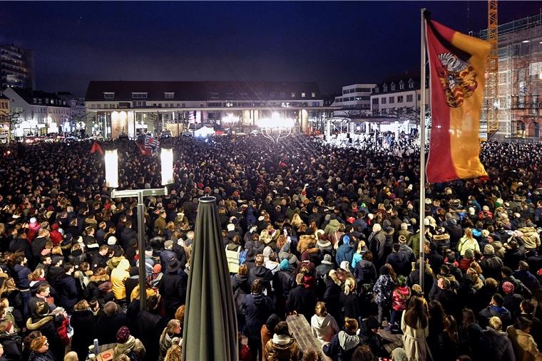 Tausende Menschen hören Bundespräsident Steinmeier bei einer Trauerveranstaltung auf dem Marktplatz in Hanau zu.