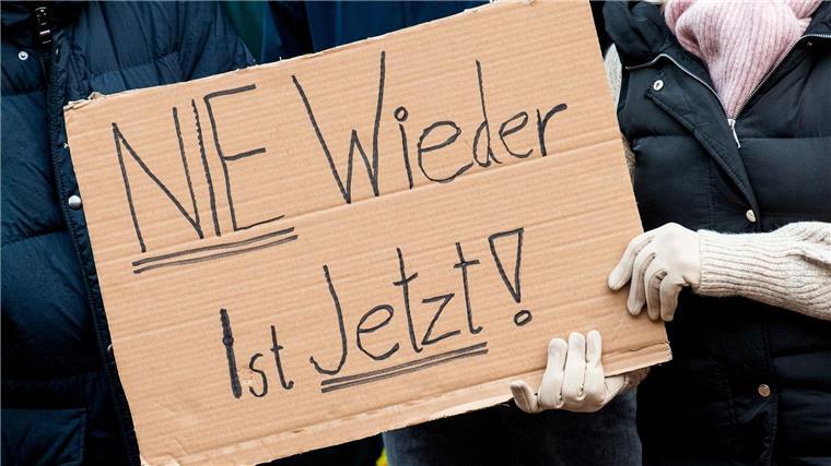 Teilnehmer einer Demonstration gegen Rechtsextremismus halten ein Schild in den Händen.