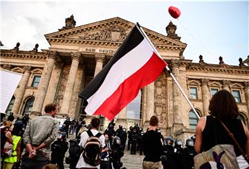 Teilnehmer einer Kundgebung gegen die Corona-Maßnahmen stehen vor dem Reichstag, ein Teilnehmer hält eine Reichsflagge.