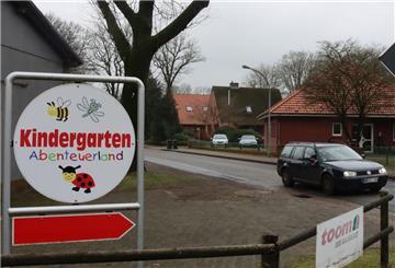 Ein dunkles Auto fährt am Ostertimker Kindergarten vorbei.