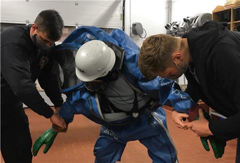 Theorie-Stunde bei der Freiwilligen Feuerwehr von Düring: Der Einsatz im Chemikalien-Schutzanzug. Gruppenführer Sebastian Guderian (links) und Marc Wahlers (rechts) helfen Leon Jack Schröder beim Anziehen.