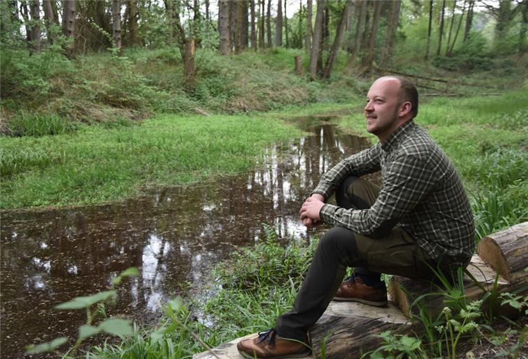 Das Foto zeigt Thorben Rievesehl an einem Teich im Wald sitzend.  