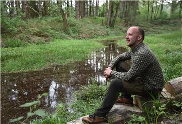 Das Foto zeigt Thorben Rievesehl an einem Teich im Wald sitzend.  
