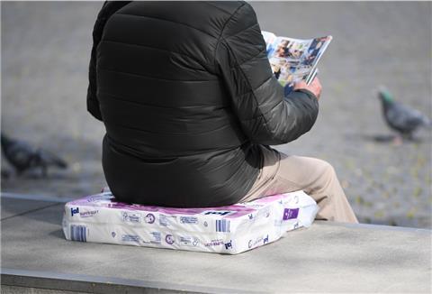 Mann sitzt auf einer Packung Toilettenpapier