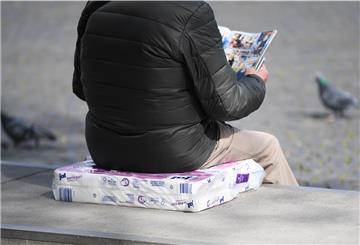 Mann sitzt auf einer Packung Toilettenpapier